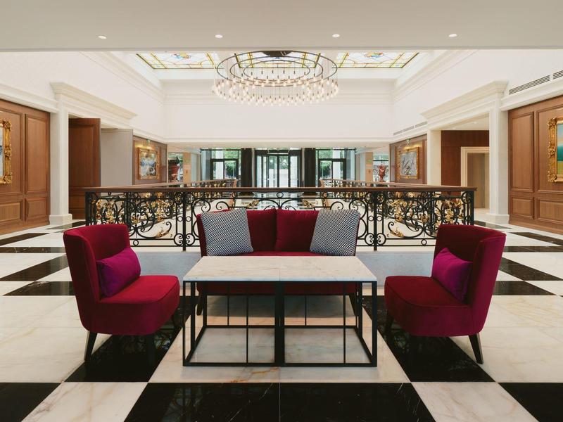 Área de vestíbulo elegante con sillones rojos y mesa sobre suelo blanco y negro