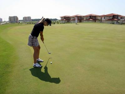A person playing golf on a well-maintained golf course in sunny weather.