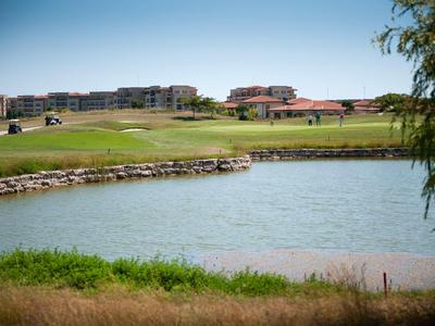 Golf course with water hazard and buildings in the background under clear sky