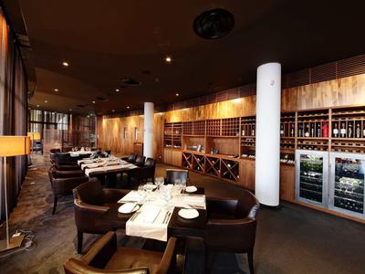 Elegant restaurant interior with dark wood, warm lighting, and modern design.