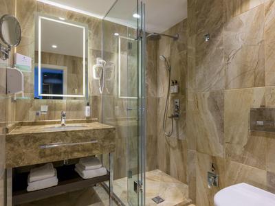 Bagno moderno con specchio illuminato e parete in piastrelle di pietra beige.