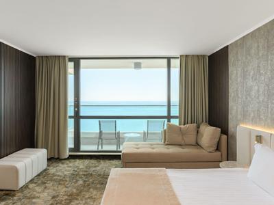 Camera d'albergo arredata modernamente con vista mare e balcone.