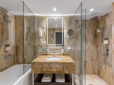 Bagno di lusso in hotel con marmo, doppia doccia e grande specchio.