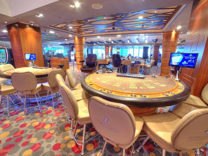 Salle de casino élégante avec tables de poker, chaises confortables et ambiance moderne.