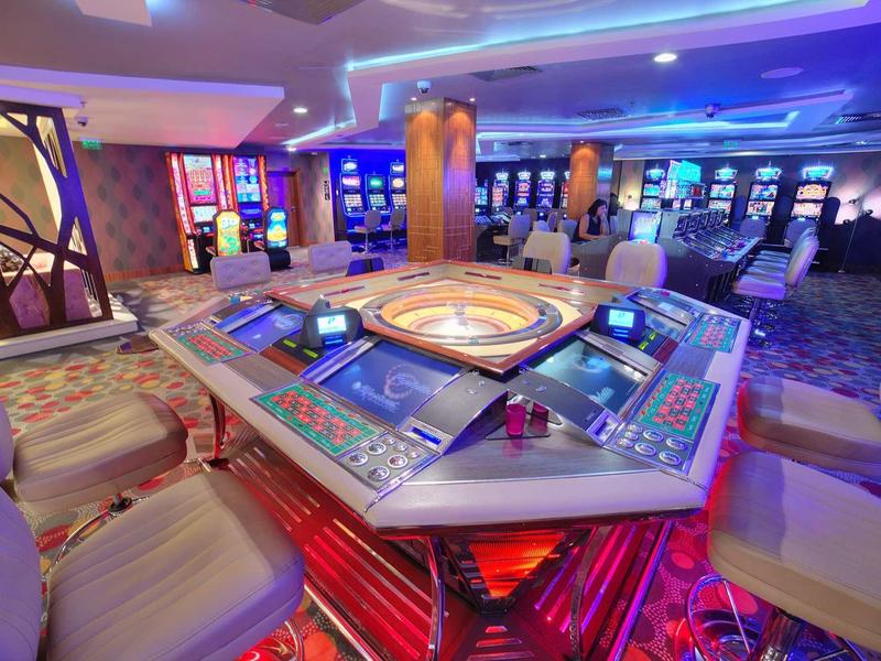 Table de roulette au design moderne dans un casino éclairé avec des chaises.