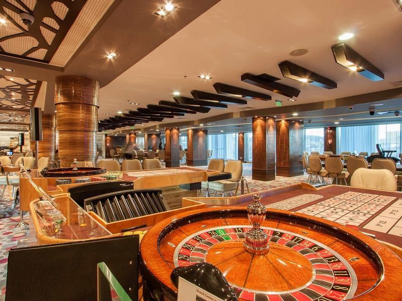 Espace casino luxueusement aménagé avec table de roulette et sièges confortables.