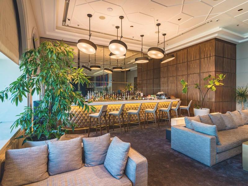 Bar d'hôtel confortable avec canapés modernes, éclairage élégant et plantes décoratives.