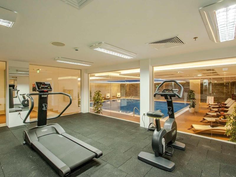 Salle de sport moderne avec tapis roulant et vélo d'appartement à côté de la piscine intérieure.