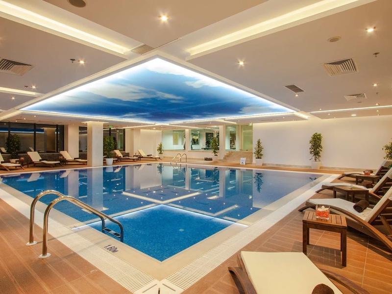 Piscine intérieure élégante avec plafond ciel et chaises longues pour la détente.