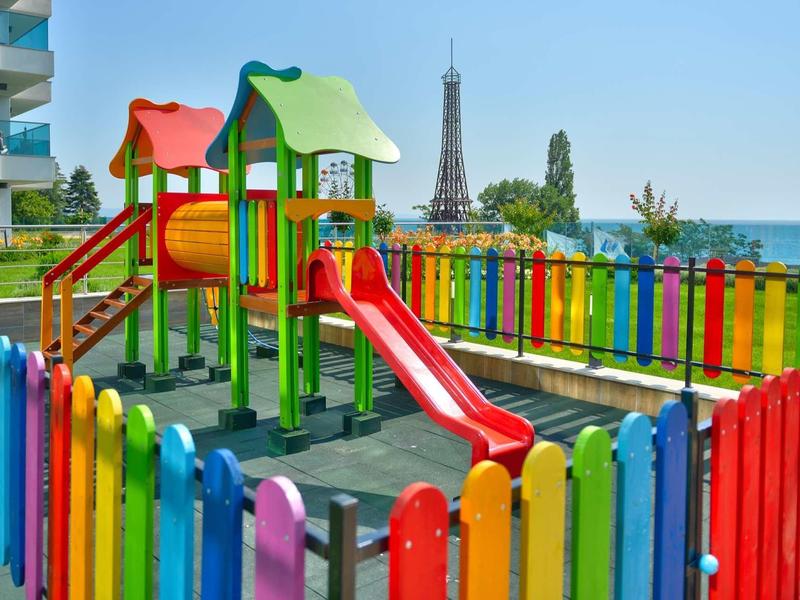 Aire de jeux colorée avec toboggan et structure d'escalade, tour Eiffel en arrière-plan