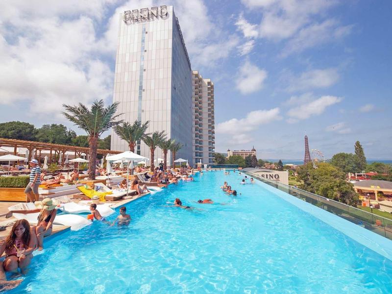 Piscine à débordement avec hôtel et clients se détendant et profitant du soleil.