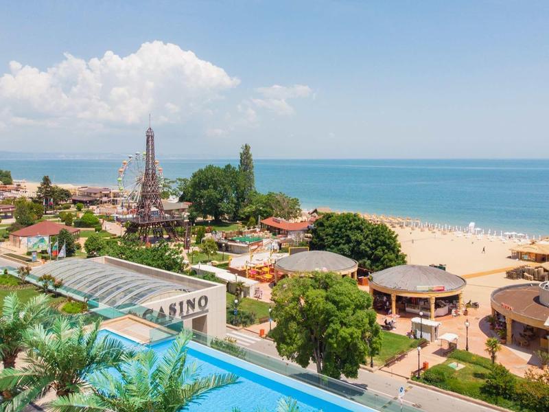 Vue sur une plage, une piscine et une station balnéaire avec casino sur la côte sous un ciel clair