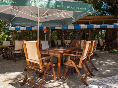 Tavolo in legno con diverse sedie sotto ombrelloni in un cortile lastricato