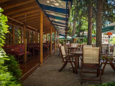 Area pranzo all'aperto con tavoli e sedie in legno sotto un passaggio coperto e all'aperto.