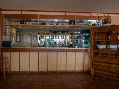 Un bar dell'hotel con un lungo bancone, sgabelli e una rastrelliera per vino, tutto in tonalità calde di legno.