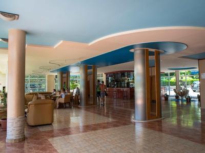 Ampia hall dell'hotel con aree salotto, colonne e un bar sullo sfondo