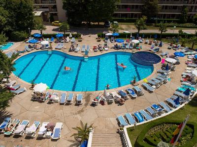 Großer, unregelmäßig geformter Außenpool mit blauen Liegestühlen und Sonnenschirmen im Umfeld.