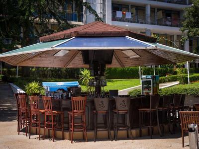 Area bar esterna rotonda con sedie di legno e ombrellone in una giornata di sole