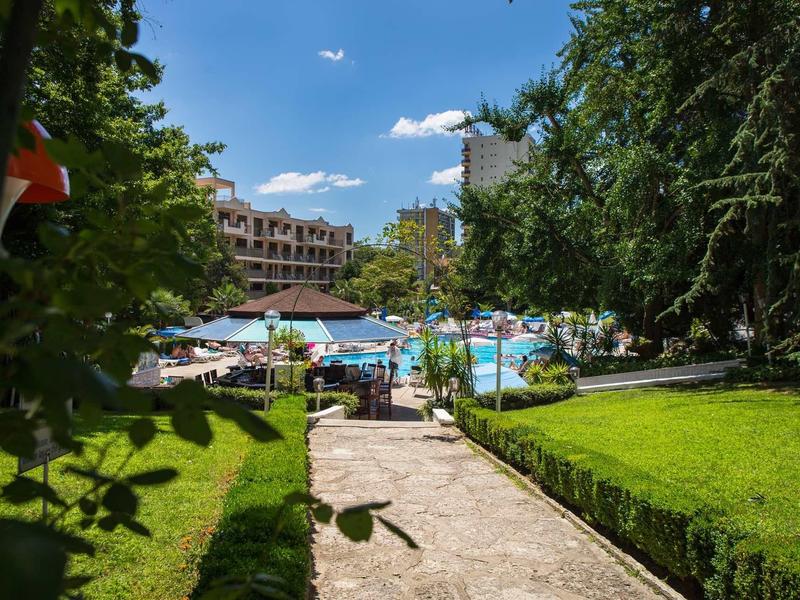 Ein sonniger Tag am Pool mit Liegestühlen, Bäumen und Gebäuden im Hintergrund.