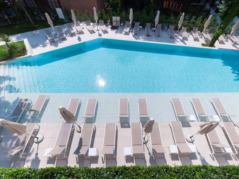Aantrekkelijk buitenzwembad met ligstoelen en parasols op een zonnige dag.