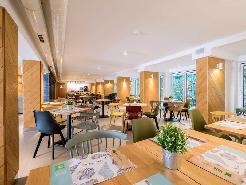 Lichte, moderne eetruimte met verschillende zitmogelijkheden en planten in een hotel.