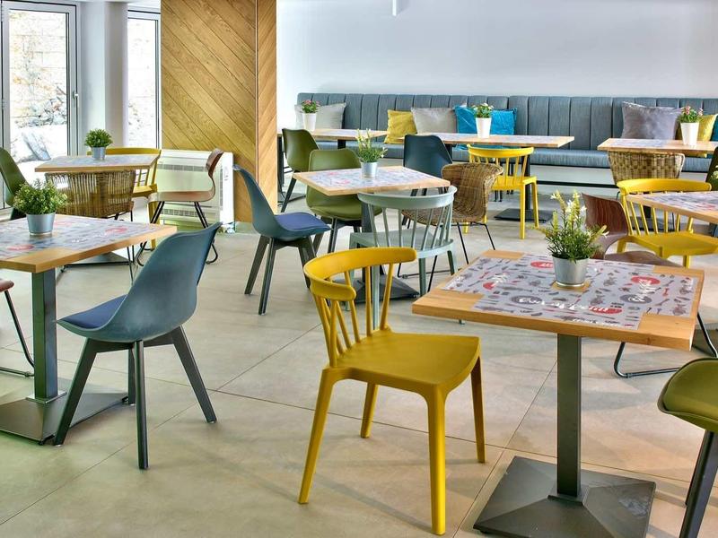 Moderne eetruimte met kleurrijke stoelen en tafels, helder en uitnodigend ontwerp.