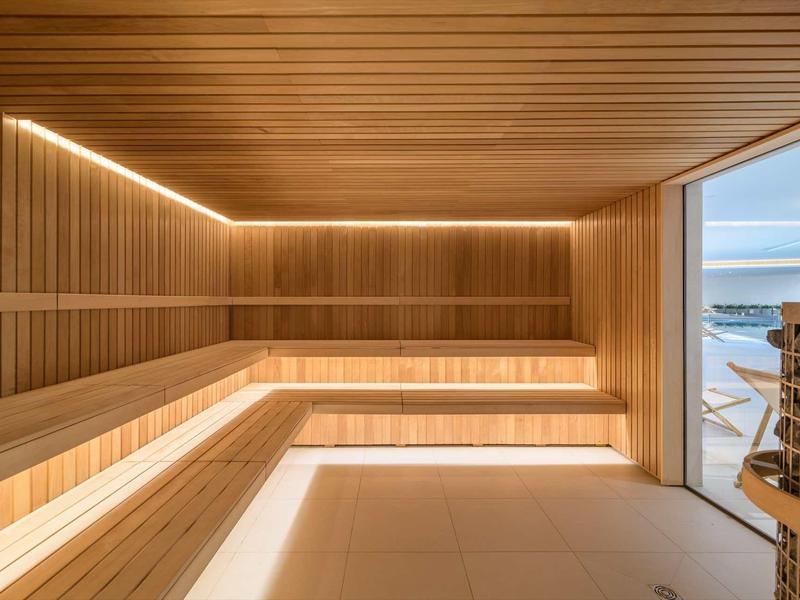 Modern sauna with wooden paneling and view of a terrace overlooking the sea.