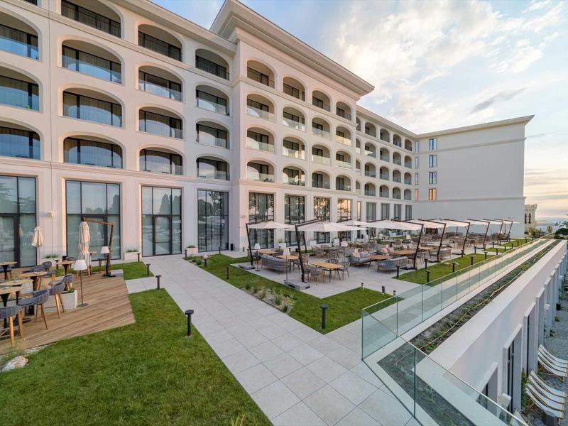 Large hotel with terraces and outdoor seating at sunset.