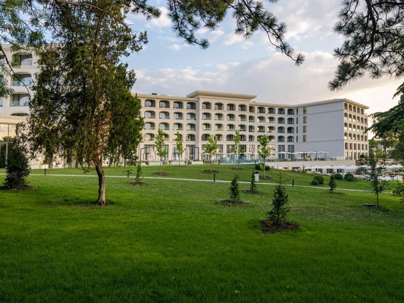 Large multi-story hotel building surrounded by green lawns and trees.