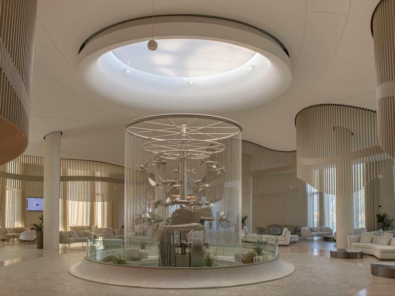 Bright hotel lobby with large glass centerpiece and circular skylight