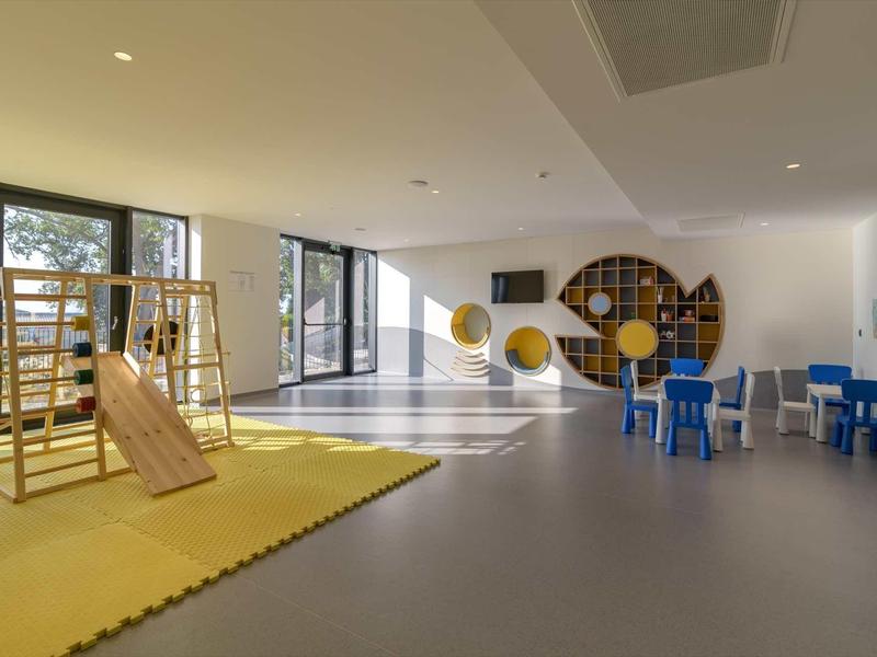 Bright modern playroom with climbing wall, blue kids' table, and large windows.