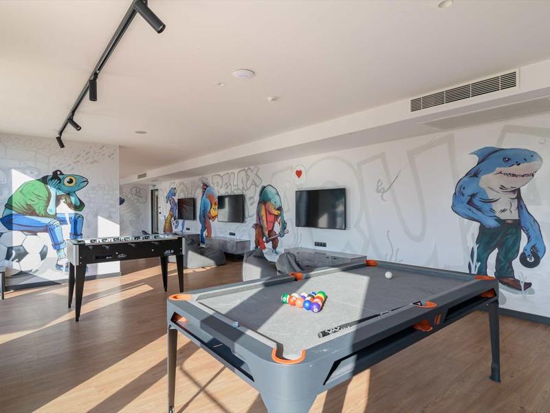 Recreation room with pool table, foosball, and wall graffiti in a modern hotel.