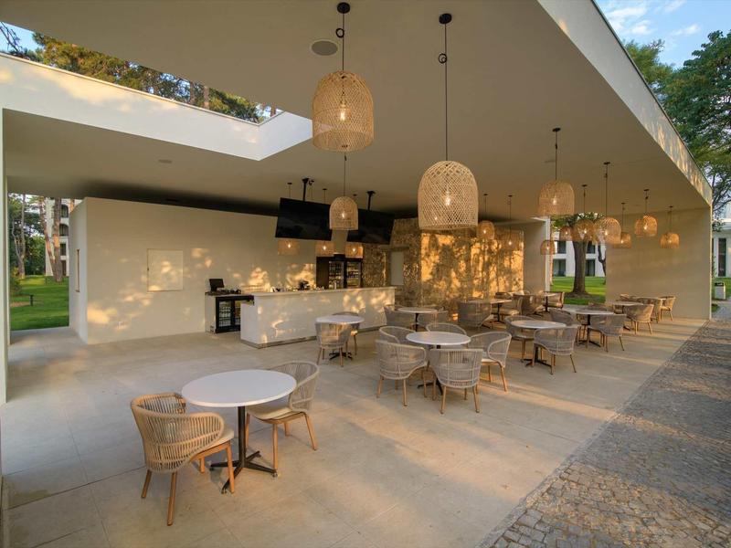 Open lounge area with tables, chairs, and modern lighting in a hotel setting.