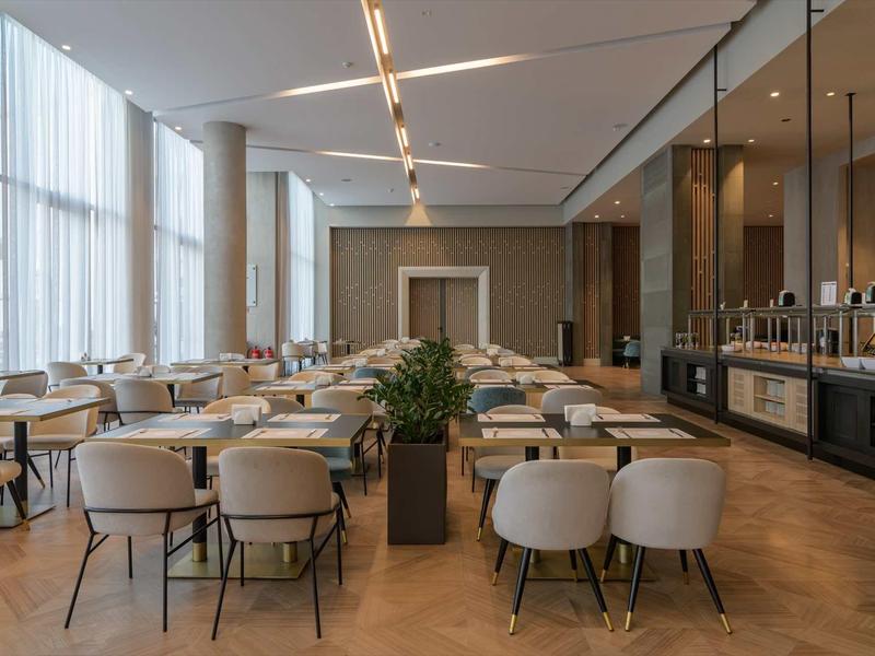 Modern hotel restaurant with stylish chairs, wooden floor, and large windows.