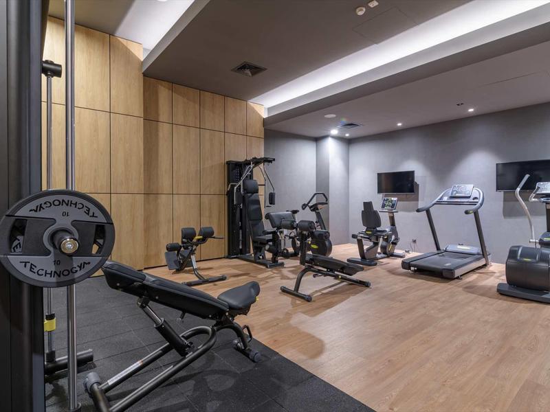 Modern gym with treadmills, exercise bikes, and weights in a hotel.