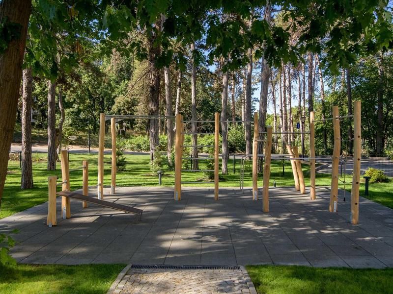 Outdoor fitness area with wooden equipment in a shaded park