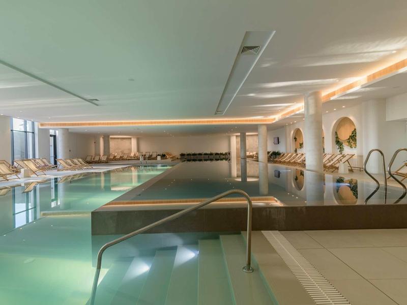 Modern indoor pool with clean lines, lounge chairs, and a relaxing atmosphere in a hotel.