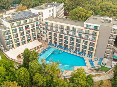 Modern hotel met groot buitenzwembad omgeven door bomen in een groen landschap