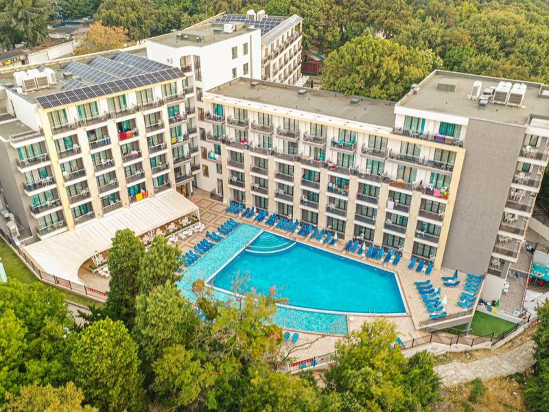 Modern hotel met groot buitenzwembad omgeven door bomen in een groen landschap