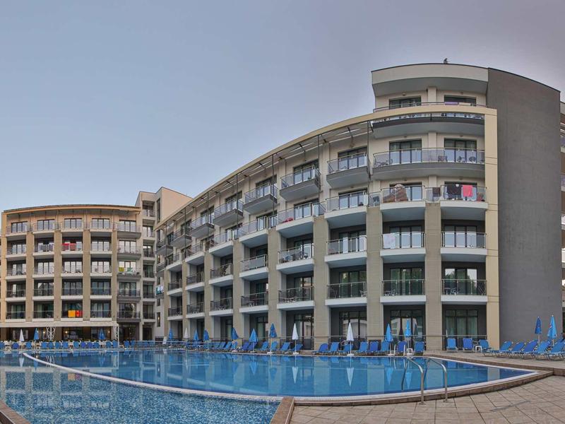 Modern hotel met meerdere verdiepingen en groot buitenzwembad bij heldere lucht.