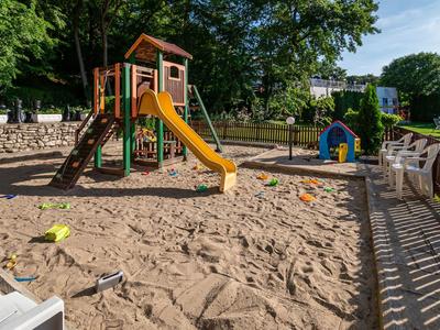 Kinderspielplatz mit Sandkasten, Rutsche und Klettergerüst in einer Outdoor-Umgebung.