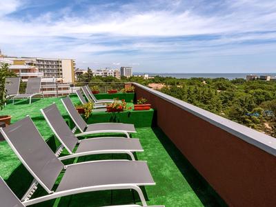 Terrasse sur le toit avec chaises longues, vue sur la mer et les bâtiments environnants
