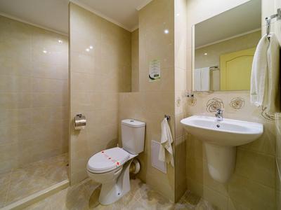 Kleines Badezimmer mit Dusche, WC, Waschbecken und Handtüchern an den Wänden.