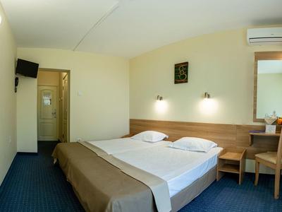 Helles Hotelzimmer mit Doppelbett, Schreibtisch, Stuhl und Klimaanlage.