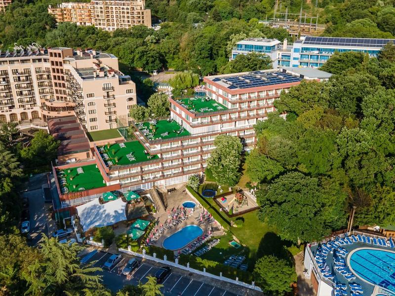 Blick aus der Luft auf ein Hotelresort mit Pools, umgeben von Bäumen und anderen Gebäuden.