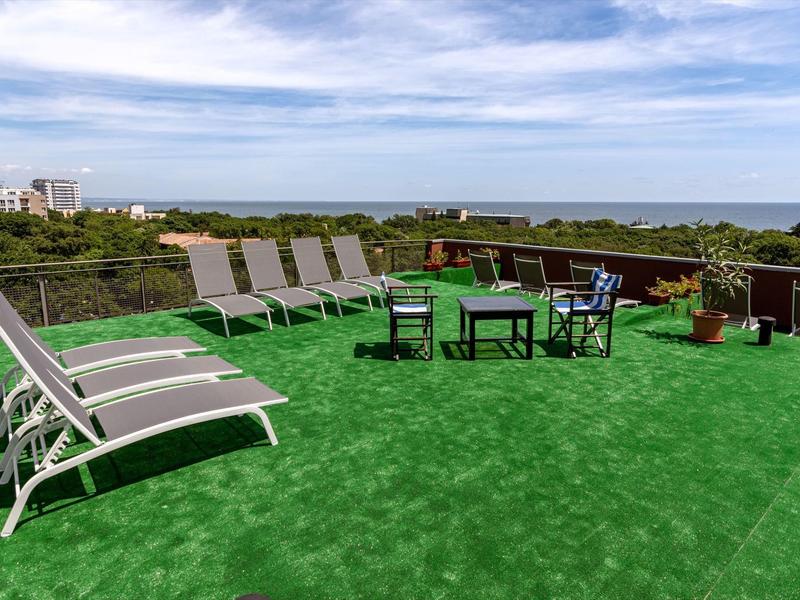 Dachterrasse mit Liegestühlen und Sitzgruppe mit Blick auf das Meer und den Himmel.