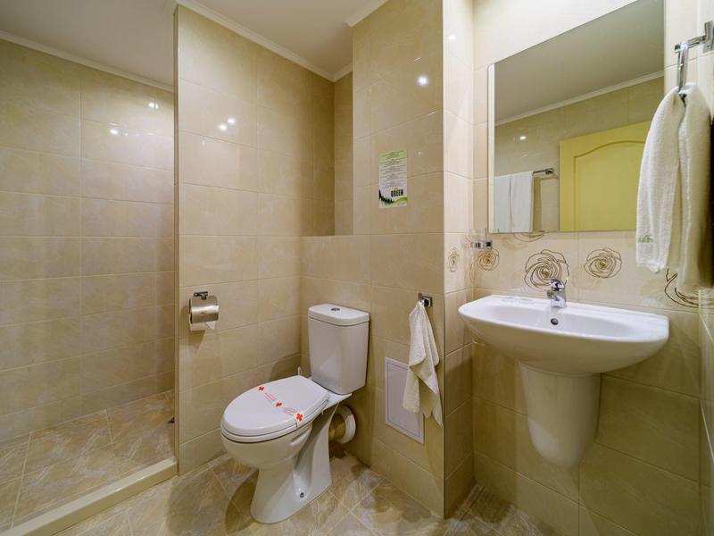 Kleines Badezimmer mit Dusche, WC, Waschbecken und Handtüchern an den Wänden.