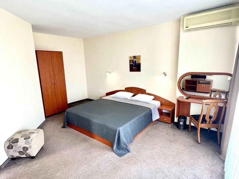 Ein einfach eingerichtetes Hotelzimmer mit Doppelbett, Schreibtisch und Kleiderschrank.