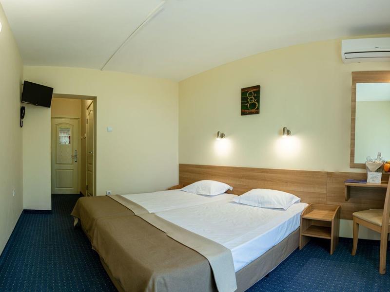 Helles Hotelzimmer mit Doppelbett, Schreibtisch, Stuhl und Klimaanlage.