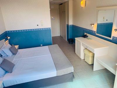 Jasny pokój hotelowy z łóżkiem podwójnym, niebiesko-białymi ścianami i biurkiem z lustrem.